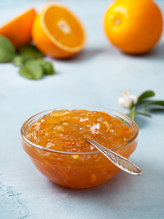 orange jam in a glass bowl, fresh oranges on a blue background.の写真素材