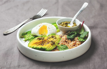healthy diet breakfast. quinoa, avocado, asparagus, poached egg and pesto in a white ceramic plate on a gray napkinの写真素材