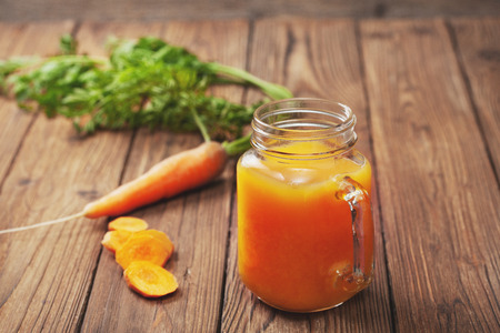Carrot juice in a glass jar on an old wooden background closeupの写真素材