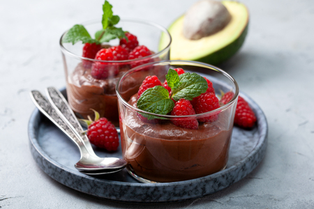 Avocado chocolate mousse with raspberries in glass serving glasses on an grayの写真素材