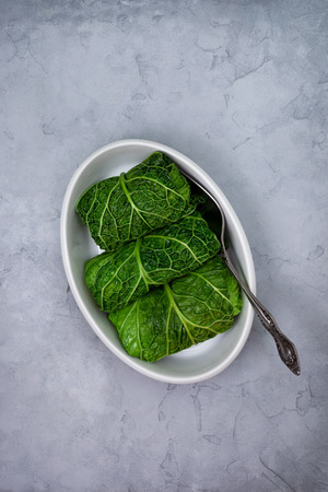 Stuffed savoy cabbage in white bowl for baking on grayの写真素材