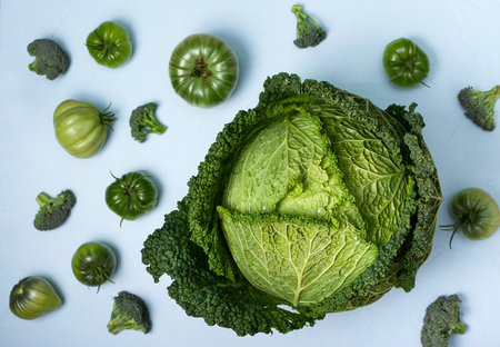 Green vegetables: savoy cabbage, broccoli, green tomatoes on a blueの写真素材