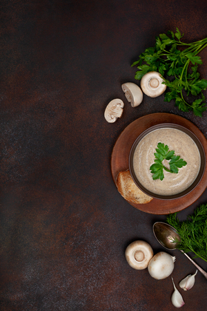 Mushroom soup in a brown bowl, parsley, croutons on a brownの写真素材