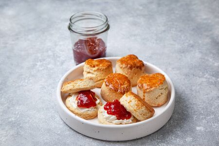 scones on a white plate, a jar of strawberry jam on a gray backgroundの写真素材