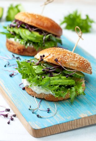 green burger with avocado, cucumber, cream cheese and micro greens on a blue boardの写真素材