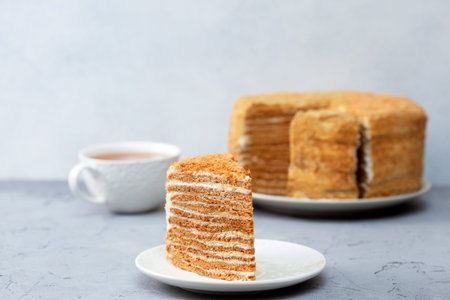 piece of homemade honey cake on a white plate on a gray concrete background