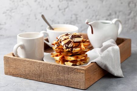 Belgian waffles topping with banana and chocolate sauce on a gray backgroundの写真素材