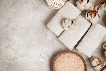 Three cotton towels, cotton branches, a bowl of salt on a concreteの写真素材