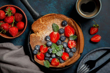 dutch baby pancake with berry in a cast-iron pan on a blue background. view from aboveの写真素材