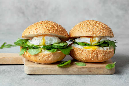 poached egg sandwich, fresh cucumber, spinach and cream cheese on a boardの写真素材