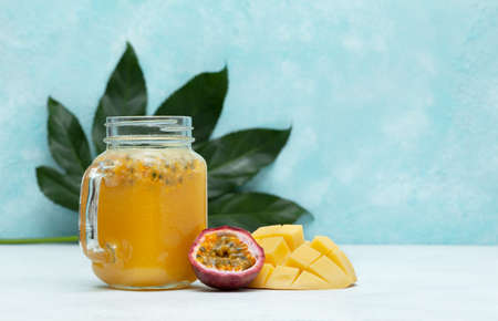 tropical smoothie mango and passionfruit in a jar mason, fresh mango and passionfruit on a blue backgroundの写真素材