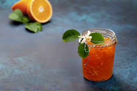 orange jam in a glass jar, orange pieces on a blue backgroundの写真素材