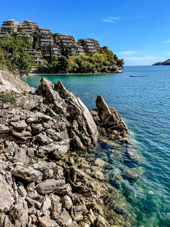 A beautifully tranquil coastal view showcasing rocky shores alongside calm, azure waters beneath a clear skyの写真素材