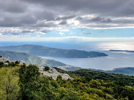 A breathtakingly stunning panoramic view showcasing majestic mountains meeting the vast sea under a cloudy skyの写真素材