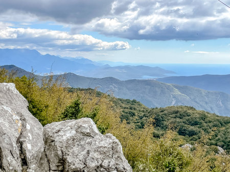 A captivating and stunning panoramic view featuring majestic mountains and a vast sea under a cloudy skyの写真素材