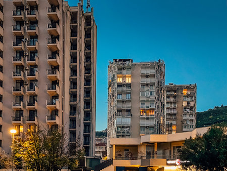 Twilight cityscape with illuminated apartment blocks, Evening city view showcasing aged buildings and peaceful streetsの写真素材