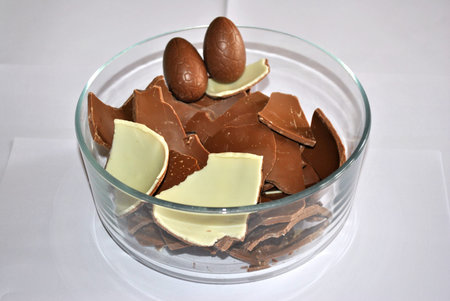 Easter Eggs chocolate. Cracked Eggs chocolate of glass container, white background. Milk and White...