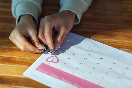 Close-up of a woman marking the date on a calendar.の写真素材