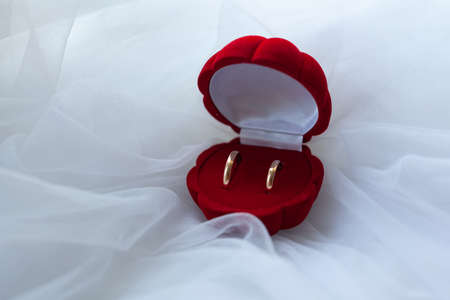 Wedding rings in a red box on a white fabric backgroundの写真素材