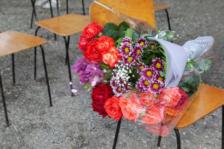 A bouquet of flowers lying on a chair outside in a sunny summer day.の写真素材
