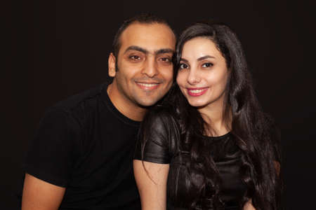 Family portrait of a young couple on a black background. Studio Portraitの写真素材