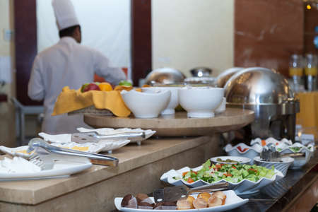 Buffet in the hotel restaurant.Chef cooking a meal in the background.Food on the display. High quality photoの写真素材