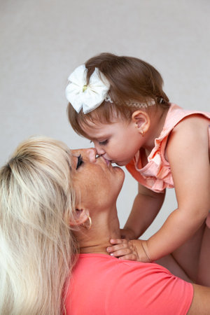 A young mother holds a little daughter in her arms and kisses her on the lips. High quality photoの写真素材