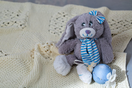 An ivory knitted baby blanket with a pronounced texture of the pattern and a soft toy on it. Window...