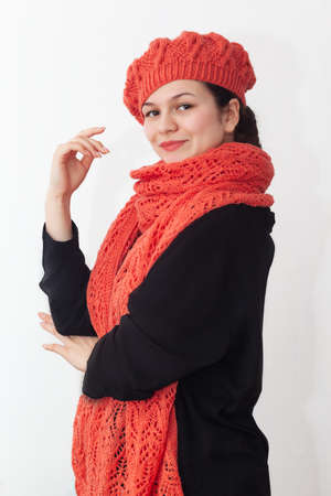 Portrait of a young girl in an orange knitted beret with a long scarf on a white background. High quality photoの写真素材