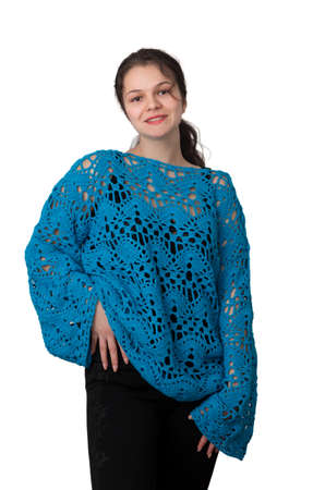 Portrait of a young girl in a blue knitted openwork jumper on a white background.の写真素材