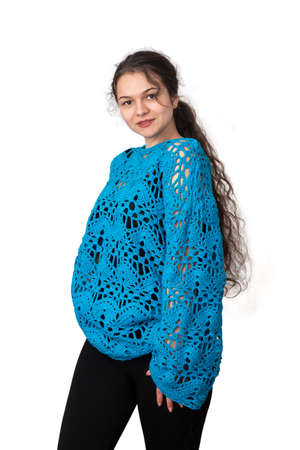Portrait of a young girl in a blue knitted openwork jumper on a white background. Knitted fashion.の写真素材