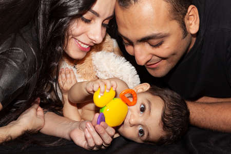 Closeup studio family portrait of a young loving couple with cute baby. Black background.の写真素材
