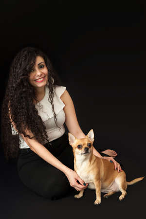 Portrait of a young woman with a chihuahua dog on a black background. High quality photoの写真素材