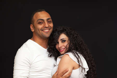 Portrait of a young couple in white t-shirts on a black background. High quality photoの写真素材