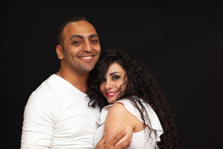 Portrait of a young couple in white t-shirts on a black background. High quality photoの写真素材
