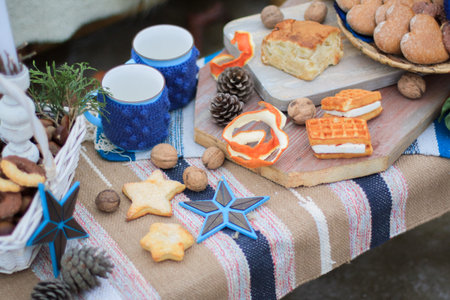 Winter decor sweet table. Mugs with cocoa and marmoslou. Sweets and nuts. The peel of an orange....