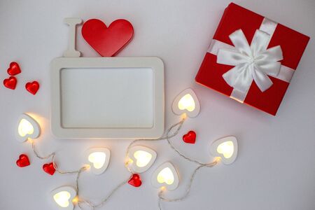 A white empty rectangular photo frame with a red heart and red gift boxの写真素材
