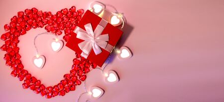 Red gift box , bright white heart-shaped garlands on a pink background. Bannerの写真素材