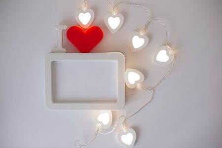 A white empty rectangular photo frame with a red heart at a white background.の写真素材