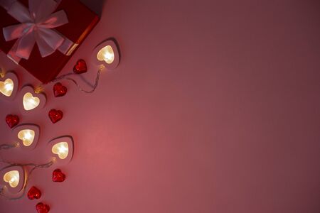 Red gift box , bright white heart-shaped garlands on a pink background.の写真素材