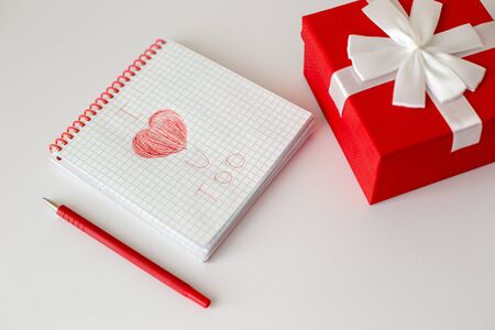 A white notebook and a red pen lie on a white table.の写真素材