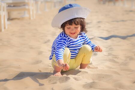 Cute little girl a plays in the sand on the beachの写真素材