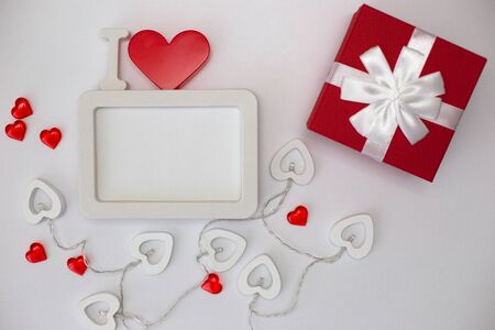 A white empty rectangular photo frame with a red heart and red gift boxの写真素材