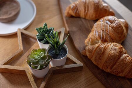 Three large croissants lie on a wooden board on the table.の写真素材