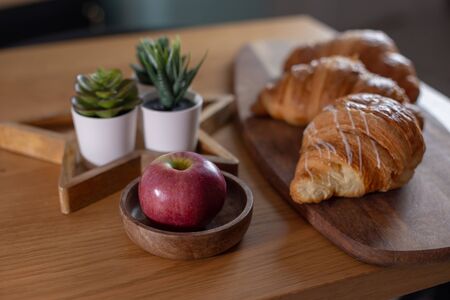 Succulents, croissants, red apple on a wooden tableの写真素材