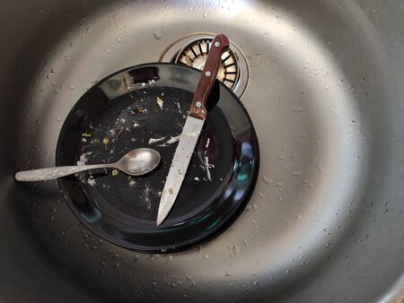 Dirty black plate in a gray sinkの写真素材