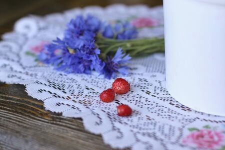 Three berries of wild strawberry lie on a knitted napkinの写真素材