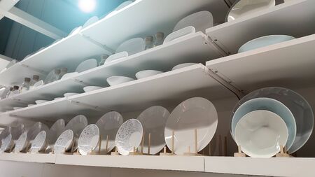 Many white plates stand on white shelves of display cases. Horizontal. Wideの写真素材