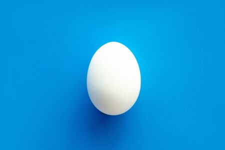 One white egg on a blue background. Top view. Isolated. Copy spaseの写真素材