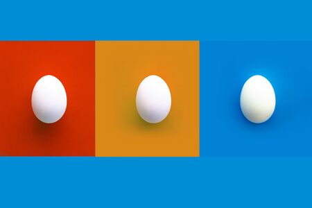 Collage of red, orange and blue rectangles with three white chicken eggs. Blue background. Copy space. Top viewの写真素材